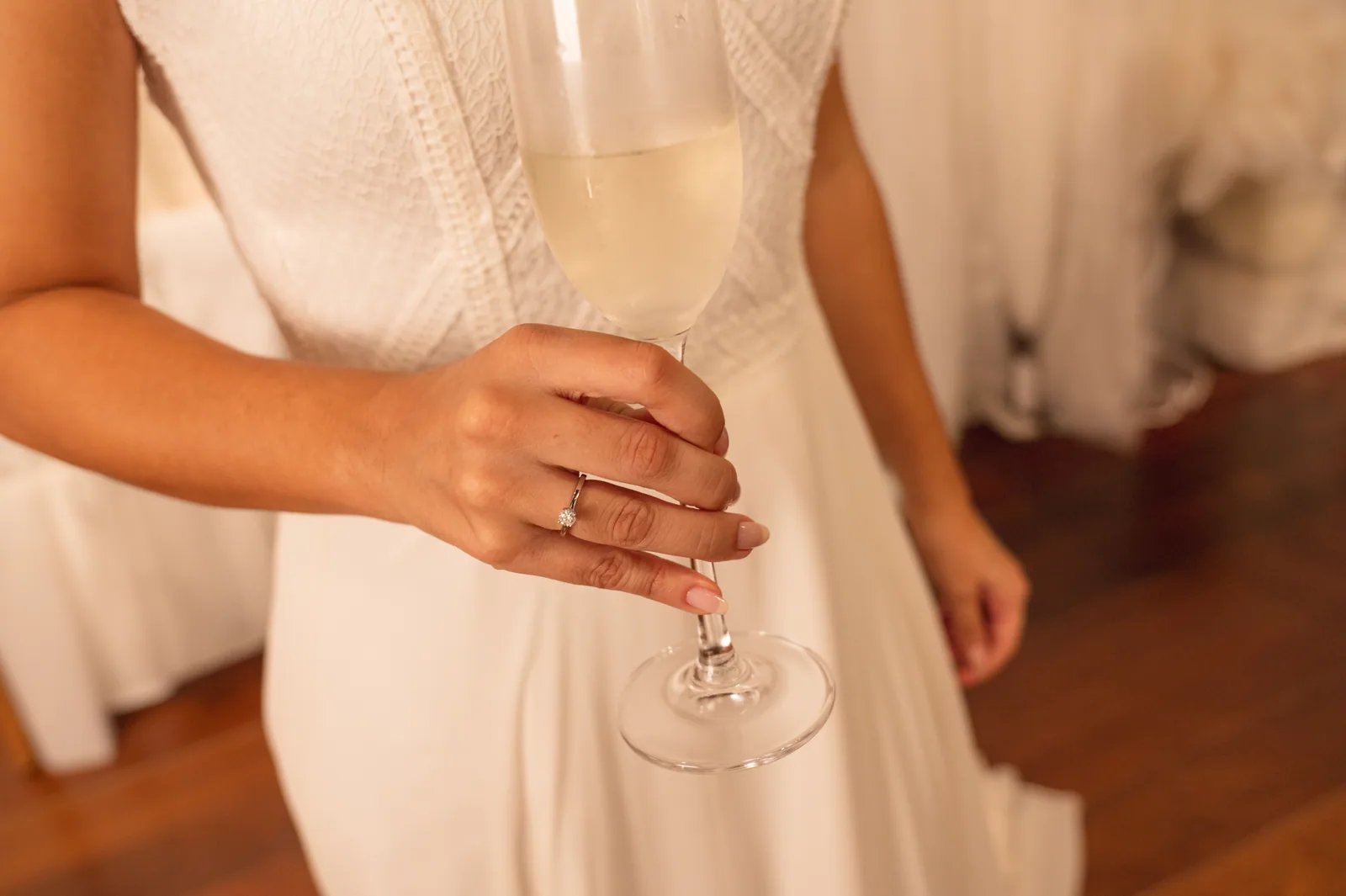 Noiva de vestido branco segurando uma taça de espumante na Casa Belina